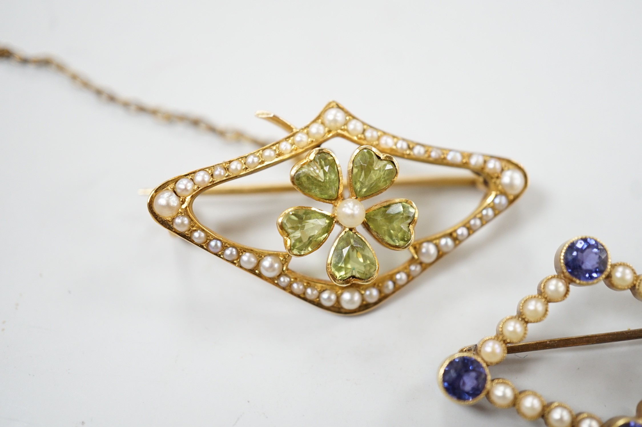 An Edwardian 15ct, peridot and seed pearl set brooch, 36mm and a similar sapphire and split pearl set brooch, gross weight 8.1 grams.